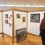 An attendee of the invitational gathering on Saturday, April 29, 2023 at the Norman Lowell Art Gallery in Anchor Point, Alaska views a display of photographs and information on Lowells life and career. Photo by Delcenia Cosman