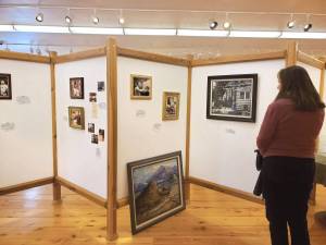 An attendee of the invitational gathering on Saturday, April 29, 2023 at the Norman Lowell Art Gallery in Anchor Point, Alaska views a display of photographs and information on Lowells life and career. Photo by Delcenia Cosman