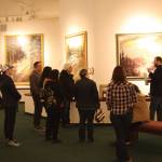 Curator Barnabas Firth (right) tells stories of artworks by Norman Lowell to attendees of the invitational gathering on Saturday, April 29, 2023 at the Norman Lowell Art Gallery in Anchor Point, Alaska. Photo by Delcenia Cosman