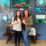 Daughter and mother, Emma and Tracy Early, with their earrings and Tracys paintings at Art Shop Gallery on May 5, 2023, in Homer, Alaska. (Photo by Christina Whiting/Homer News)
