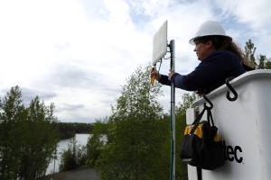 An Alaska Communications technician installs a customer premise device to a home in Sterling, Alaska. This device communicates with a nearby tower, serving the customer with a high-speed internet connection. Photo courtesy of Alaska Communications