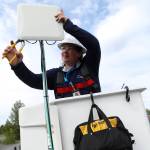 An Alaska Communications technician installs a customer premise device to a home in Sterling, Alaska. This device communicates with a nearby tower, serving the customer with a high-speed internet connection. Photo courtesy of Alaska Communications