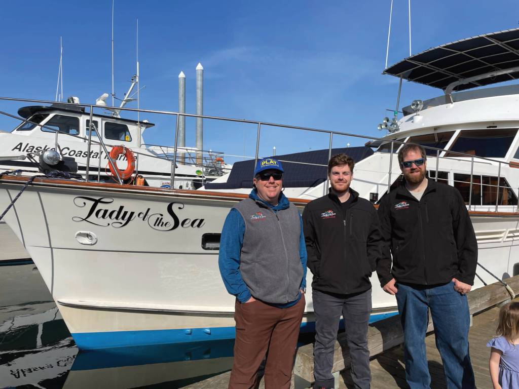 Second captain Mike Tozzo, chef Avram Salzman, and captain and owner Rand Seaton pose in front of the Lady of the Sea on Thursday, June 1, 2023 in the Homer Harbor in Homer, Alaska. Photo provided by Lauren Seaton