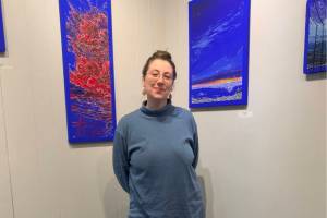 Homer artist Jenna Gerrety poses with two of the paintings in her exhibit, "Omnipresence: A Blue Period," on display at Homer Council on the Arts through June. Photo provided by Jenna Gerrety