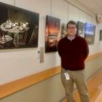 Dr. Edson Knapp is pictured n June 22, 2023 with his photography exhibit, "Joy in the Journey," on display at South Peninsula Hospital's gallery through July 4. Photo by Christina Whiting