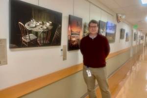 Dr. Edson Knapp is pictured n June 22, 2023 with his photography exhibit, "Joy in the Journey," on display at South Peninsula Hospital's gallery through July 4. Photo by Christina Whiting