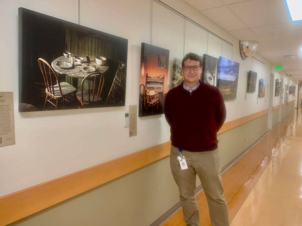Dr. Edson Knapp is pictured n June 22, 2023 with his photography exhibit, Joy in the Journey, on display at South Peninsula Hospitals gallery through July 4. Photo by Christina Whiting