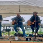 Homer youth musician Silas Jones performs on stage alongside U.S. military veteran musicians Shannon Book and Brandon Mills during the Homer Chamber of Commerce and Visitors Center Summer Solstice Festival on Wednesday, June 21, 2023 at the Deep Water Dock in Homer, Alaska. Photo by Christina Whiting