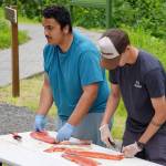 Marcus Wong and Ransom Hayes demonstrate slicing salmon fillets into strips during a smoked salmon demonstration, part of Fish Week 2023, on Wednesday, July 19, 2023, at the Kenai National Wildlife Refuge Visitor Center in Soldotna, Alaska. (Jake Dye/Peninsula Clarion)