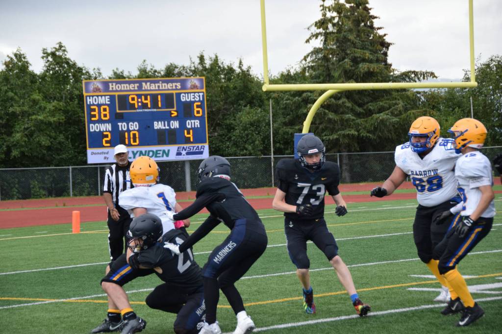 Barrows Angelo Reyes carries the ball but is tackled by Homer in the fourth quarter of the home opener game on Saturday, Aug. 12, 2023 in Homer, Alaska. (Delcenia Cosman/Homer News)