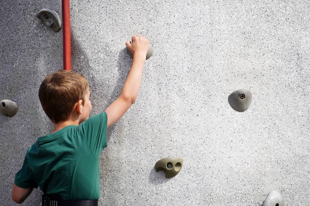 Arthur Steward, left, scales the rock wall at the Kenai Peninsula Fair in Ninilchik, Alaska, on Friday, Aug. 11, 2023. (Jake Dye/Peninsula Clarion)
