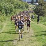Erik Thompson of Juneau-Douglas: Yadaa.at Kale leads the pack up a hill at the beginning of the boys varsity race at the Ted McKenney Invitational on Saturday, Aug. 19, 2023, at Tsalteshi Trails just outside of Soldotna, Alaska. (Photo by Jeff Helminiak/Peninsula Clarion)