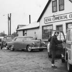 [1a—] After doing business in the Kenai Commercial Company store, Rusty Lancashire climbs into family station wagon, with its sagging back bumper, to head for home. (1954 photo by Bob and Ira Spring for Better Homes & Garden magazine)