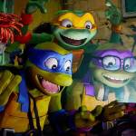 April ONeil, Leonardo, Michelangelo, Donatello and Raphael gather around a cell phone in Teenage Mutant Ninja Turtles: Mutant Mayhem. (Photo courtesy Paramount)