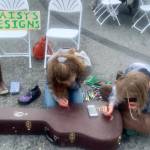 Daisy Walker (left) and her friend Leah Dunn paint a visiting musician's guitar case during the 2023 Solstice Festival on the Spit in Homer, Alaska. Photo by Christina Whiting