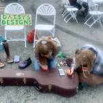 Daisy Walker (left) and her friend Leah Dunn paint a visiting musicians guitar case during the 2023 Solstice Festival on the Spit in Homer, Alaska. Photo by Christina Whiting