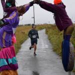 The Sealegs Stilt Troupe cheers on Michael Pedersen as he approaches the finish line in the 5K Run for Recovery on Saturday, Sept. 16, 2023 on the Spit in Homer, Alaska. (Delcenia Cosman/Homer News)