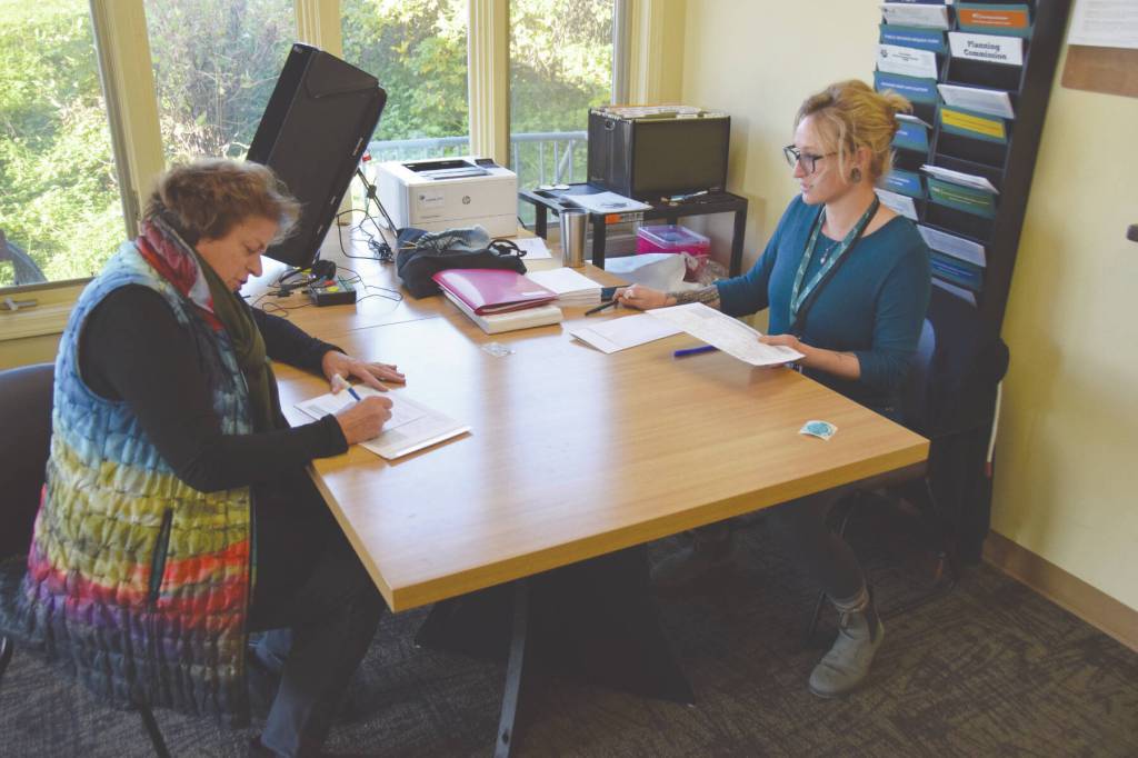 Rachel Tussey, election official with the City of Homer, helps a voter with registration on Tuesday, Oct. 3, 2023. (Finn Heimbold/ Homer News)