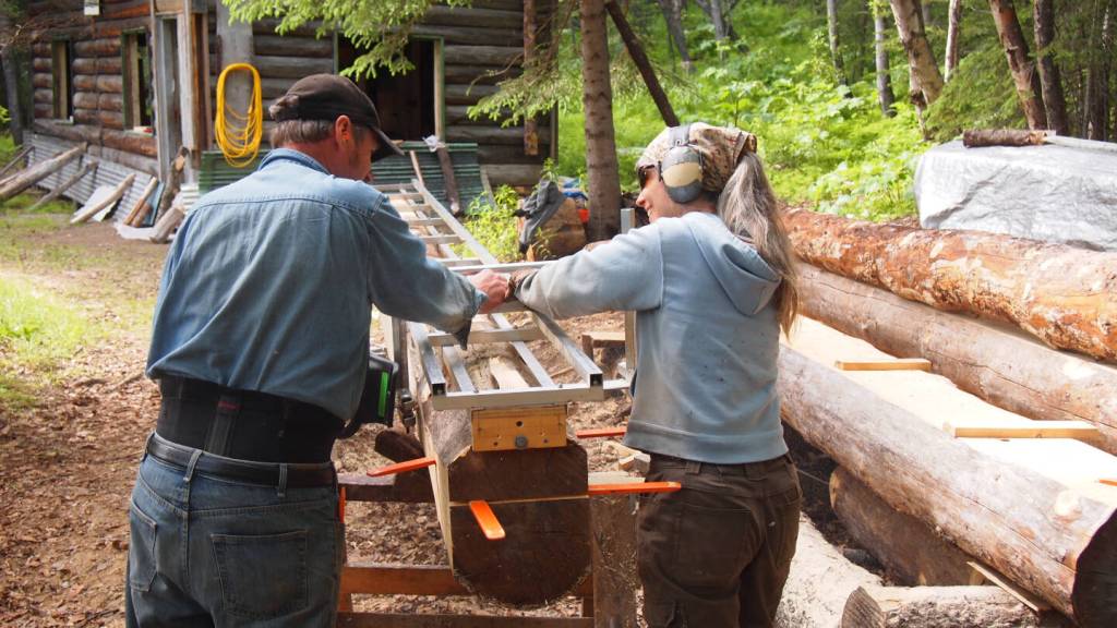Anne Coray (right) and her husband, Steve Kahn (left) mill logs during the rebuild of Brown Carlsons cabin on Lake Clark in June 2016. Photo provided by Anne Coray and Steve Kahn