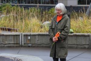 Mary Hunt, a survivor of Holy Cross Mission, holds flowers during an Orange Shirt Day ceremony at Ggugguyni T'uh, "Raven Place," outside the Dena'ina Wellness Center on Friday, Oct. 6, 2023 in Kenai, Alaska. Orange Shirt Day honors indigenous elders who survived and children lost from boarding schools established to detribalize indigenous people. (Ashlyn O'Hara/Peninsula Clarion)