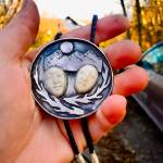 A bolo tie is hand-fabricated by Carley Conemac from sterling silver, with two water buffalo face carvings surrounded by branches and a mountainscape. Photo provided