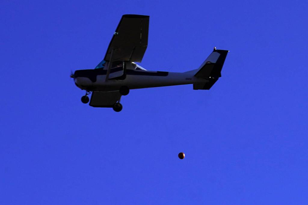 A pumpkin is released from a plane during Kenai Aviations Fifth Annual Pumpkin Drop at the Kenai Airpark in Kenai, Alaska, on Saturday, Oct. 21, 2023. (Jake Dye/Peninsula Clarion)