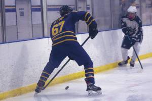 Matfey Reutov moves the puck down the rink against a Soldotna High School player on Friday, Jan. 14, 2022. (Photo by Sarah Knapp/Homer News)