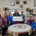 Homer Foundation executive director Mike Miller (center) presents a grant check to Anchor Point Public Library staff and board members (from left) Rachel Bice, Tressa Hidden Friend, Bobby Ness, Genevieve Winrod, Deanna Thomas, Mary Perry, Ann Bailey, Sandy Lettis and Don Bailey on Monday, Nov. 27, 2023 in Anchor Point, Alaska. (Delcenia Cosman/Homer News)
