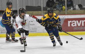 Kenai Centrals Jacob Watt and Homers Zane Barth battle for the puck Thursday, Nov. 30, 2023, at the Kenai Multi-Purpose Facility in Kenai, Alaska. (Photo by Jeff Helminiak/Peninsula Clarion)