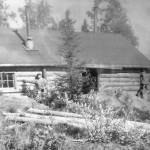 Photo courtesy of the Bodnar Family Collection
In about 1948, after he and brother Alex had proven up on his homestead and were in the process of proving up on Alexs, Marcus Bodnar poses here with his cabin along the Kenai River near the site of the bridge, which was just being built at this time.