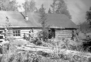 Photo courtesy of the Bodnar Family Collection
In about 1948, after he and brother Alex had proven up on his homestead and were in the process of proving up on Alexs, Marcus Bodnar poses here with his cabin along the Kenai River near the site of the bridge, which was just being built at this time.