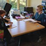 Rachel Tussey, election official with the City of Homer, helps a voter with registration before voting in the election on Tuesday Oct. 3. (Finn Heimbold/Homer News)