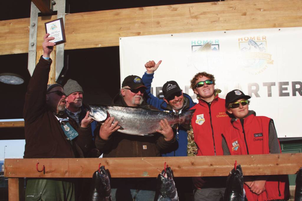 Tournament champion Gail Bilyeu (center) holds the winning fish during the Homer Winter King Salmon Tournament awards ceremony on Saturday, March 25<ins>,</ins><ins> 2023 in Homer, </ins><ins>Alaska</ins>. Pictured right are the tournaments previous two champions, Weston and Andrew Marley. Photo by Delcenia Cosman