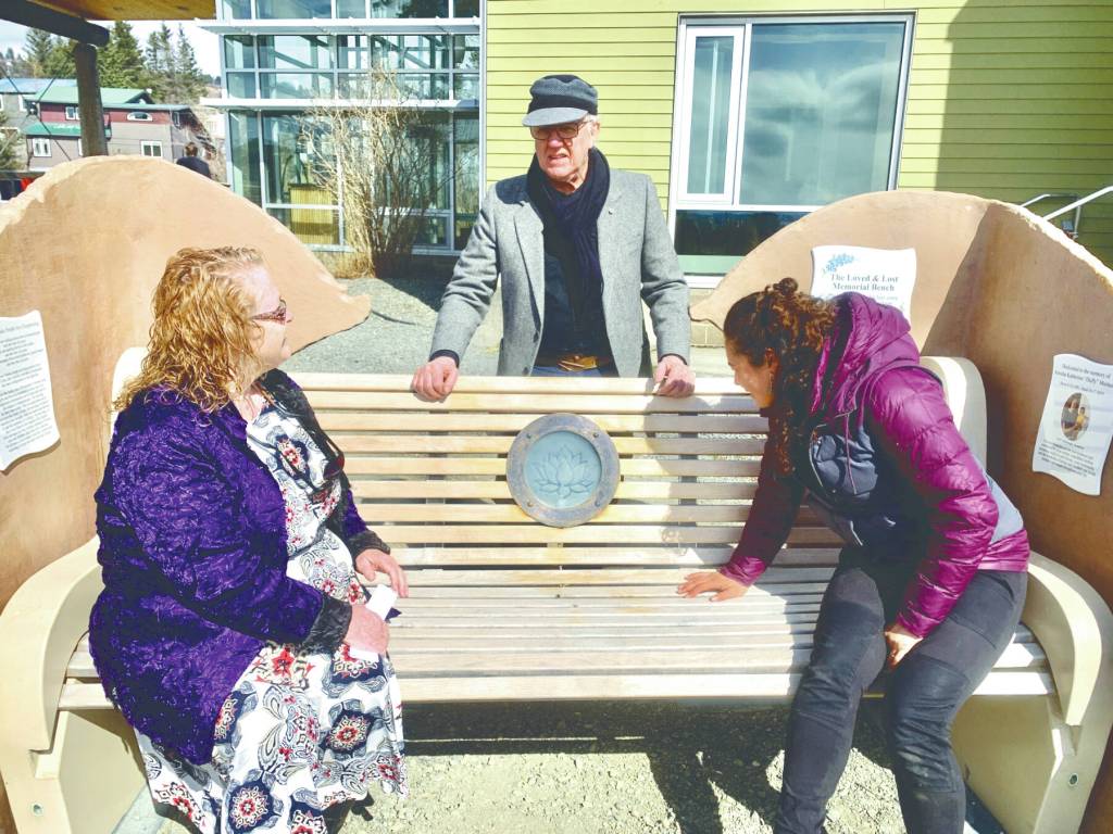Community members gathered on Wednesday, April 26 at the Homer Public Library for a ceremony to celebrate the installation of the final aspect of the Loved & Lost Memorial Bench, an etched glass and bronze lotus lamp, envisioned by artist Brad Hughes and designed and created by Art Koeninger. Photo by Christina Whiting