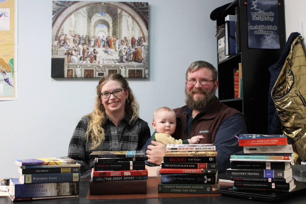 From left: Kylie Wilcox, Bernard Wilcox and Milton Wilcox sit behind the books Milton teaches at Kenai Classical School on Wednesday, Dec. 27, 2023 in Kenai, Alaska. Kylies New Years resolution for 2024 is to read all of the books on Miltons high school syllabus. (Ashlyn OHara/Peninsula Clarion)