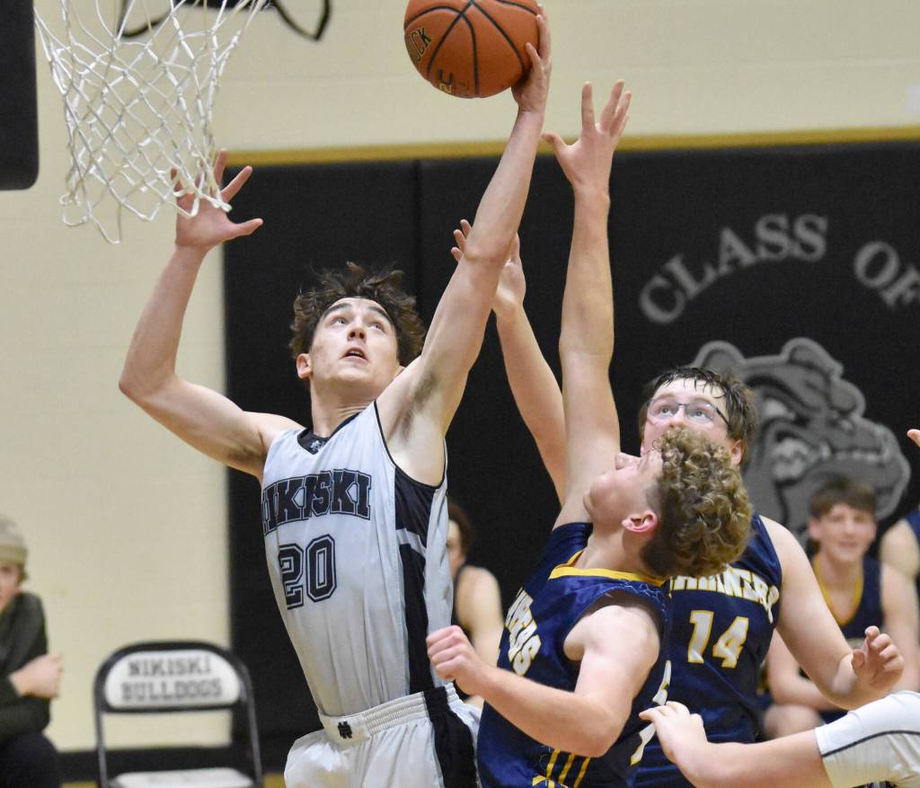 Nikiskis Dylan Hall battles for the rebound with Homers Nathan Overson and Einar Pederson on Friday, Jan. 12, 2024, at Nikiski Middle-High School in Nikiski, Alaska. (Photo by Jeff Helminiak/Peninsula Clarion)