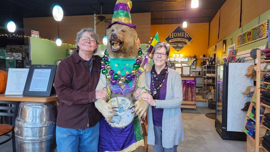 Homer Brewing Company co-owners Karen Berger (right) and Stephen McCasland pose inside the brewery with Buddy Bear, aka Mardi Buddy, in January 2024. Photo provided by Homer Brewing Company