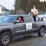 Homer Chamber of Commerce employee and parade grand marshal Marty Lanz, costumed as the infamous Homer Pennock for whom the city is named, throws chocolate coins to spectators gathered at at the 70th annual Homer Winter Carnival Parade on Pioneer Avenue on Saturday, Feb. 10, 2024 in Homer, Alaska. (Delcenia Cosman/Homer News)