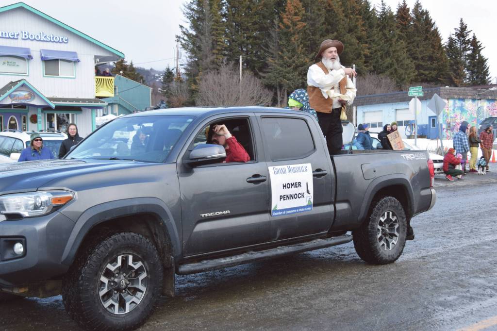 Homer Chamber of Commerce employee and parade grand marshal Marty Lanz, costumed as the infamous Homer Pennock for whom the city is named, throws chocolate coins to spectators gathered at at the 70th annual Homer Winter Carnival Parade on Pioneer Avenue on Saturday, Feb. 10, 2024 in Homer, Alaska. (Delcenia Cosman/Homer News)