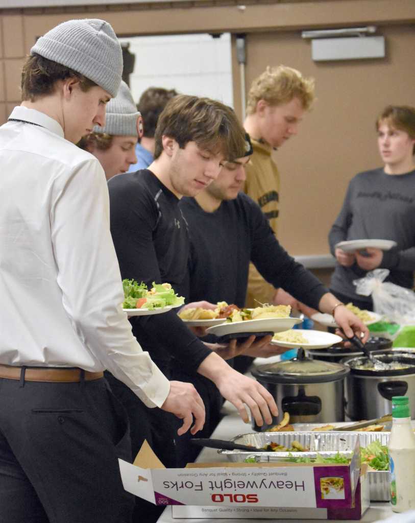 Joel Hanson and Carter McCormick lead the food line Friday, March 29, 2024, at the Soldotna Regional Sports Complex in Soldotna, Alaska. (Photo by Jeff Helminiak/Peninsula Clarion)