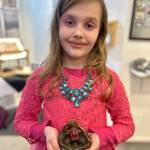 Ella Christman, 8, poses with her ceramic girl in a basket, shown during Ptarmigan Arts Youth Arts Pop Up on Friday, April 5, 2024 in Homer, Alaska. Photo by Christina Whiting