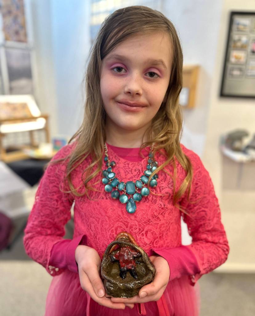 Ella Christman, 8, poses with her ceramic girl in a basket, shown during Ptarmigan Arts Youth Arts Pop Up on Friday, April 5, 2024 in Homer, Alaska. Photo by Christina Whiting