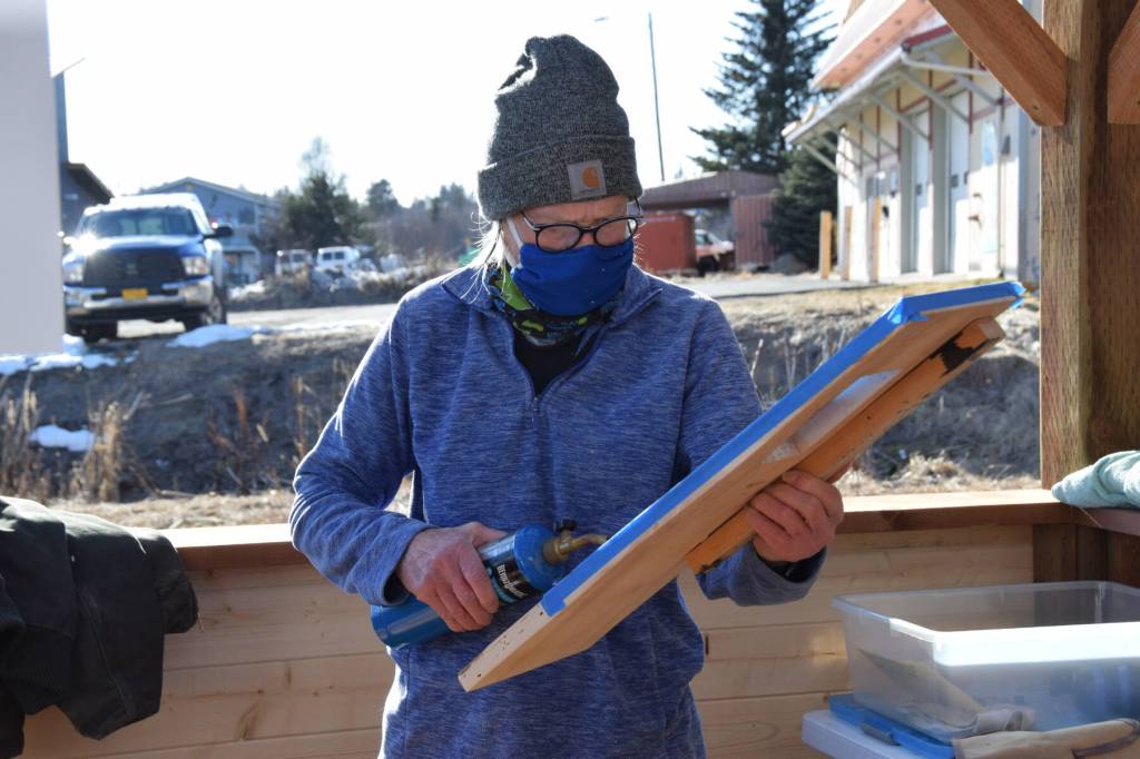 Wood sculptor Deb Lowney uses a propane torch to burn what would become an abstract wall hanging at the Ready, Set, Art! fundraiser, benefiting the Ptarmigan Arts Visual Arts Scholarship Fund, on Saturday, April 13, 2024 at Grace Ridge Brewery in Homer, Alaska. (Delcenia Cosman/Homer News)