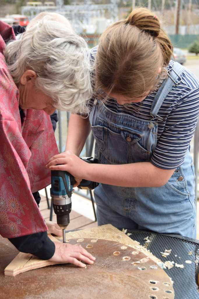 Cathy Stingley (left) and Elayna Wilson drill holes in a dried steerhide skin, which will later be soaked, formed and stretched into a taiko drumskin, during the free workshop hosted at Kachemak Bay Campus on Friday, May 3, 2024 in Homer, Alaska. (Delcenia Cosman/Homer News)
