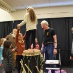 Margaret Gervais holds Yaella Bowman (center) steady while she jumps on top of the taiko drumskin in order to stretch it during the free workshop hosted at Kachemak Bay Campus on Friday, May 3, 2024 in Homer, Alaska. (Delcenia Cosman/Homer News)