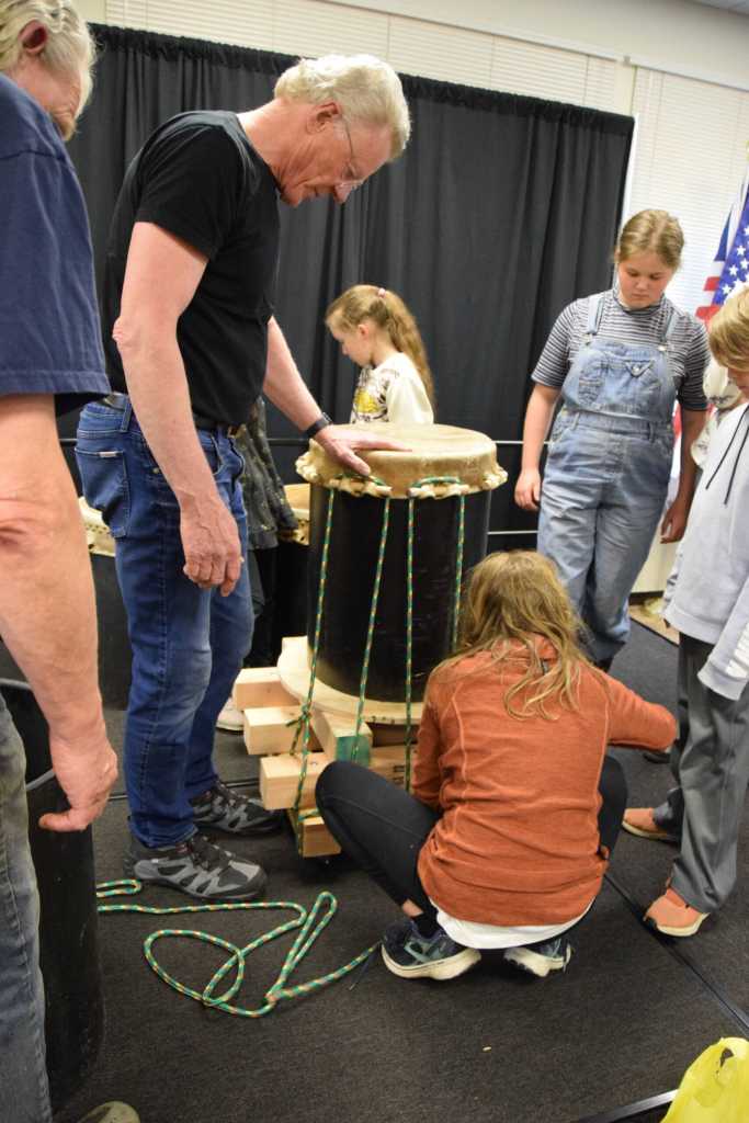 Frank Jeffries (left) teaches Alaska Japanese Club students how to secure the formed skin to the drum base in order to stretch it during the free workshop hosted at Kachemak Bay Campus on Friday, May 3, 2024 in Homer, Alaska. (Delcenia Cosman/Homer News)