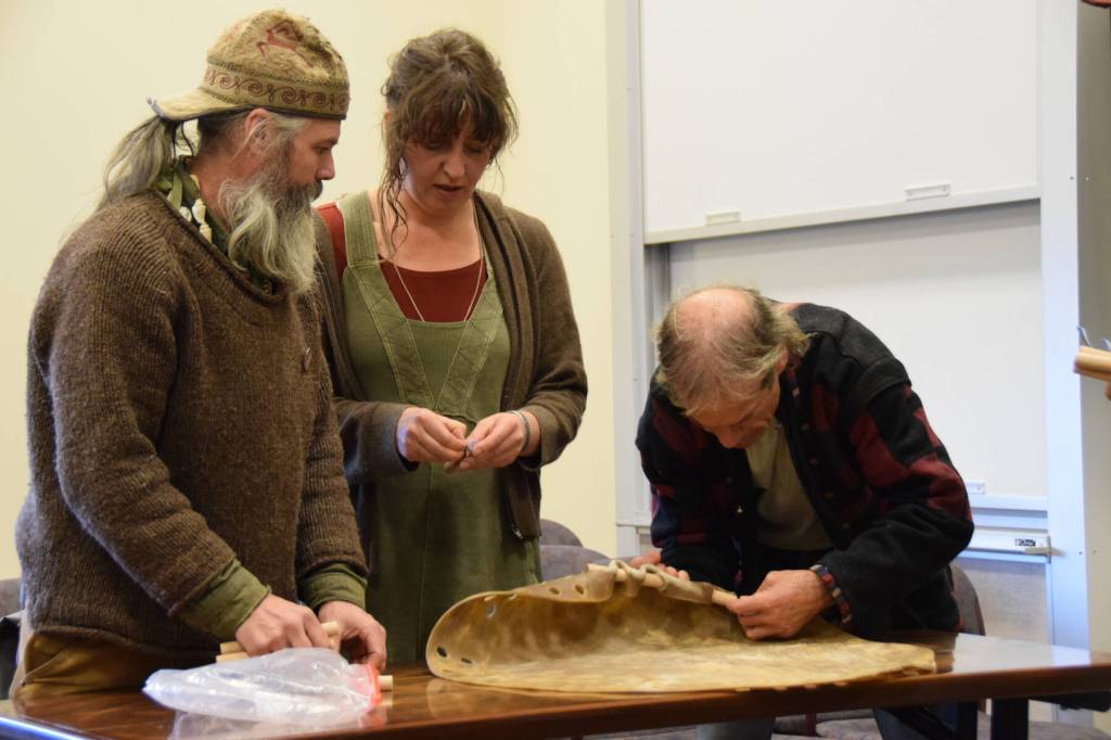 (from left to right) Lasse Holmes, Anna Wolfson and Gordy Vernon form a drum skin by inserting wooden dowls through pre-drilled holes during the free workshop hosted at Kachemak Bay Campus on Friday, May 3, 2024 in Homer, Alaska. (Delcenia Cosman/Homer News)