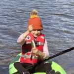 If you teach a kid to fish, she will feed you a trout breakfast every morning of the campout. This proved true for this girl, who holds up a rainbow trout while sitting on a kayak. (Photo by Leah Eskelin)