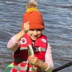 If you teach a kid to fish, she will feed you a trout breakfast every morning of the campout. This proved true for this girl, who holds up a rainbow trout while sitting on a kayak. (Photo by Leah Eskelin)
