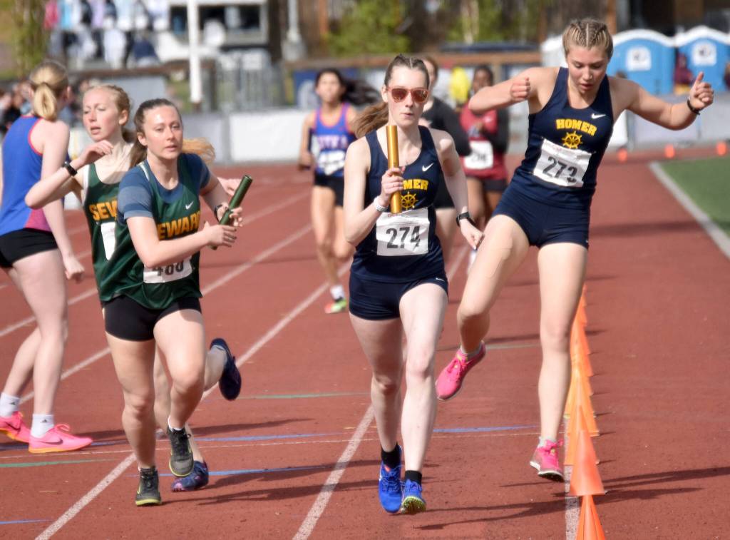 Sewards Juniper Ingalls hand to Hailey Ingalls and Homers Jaela Marchbanks hands to Beatrix McDonough in the 3,200-meter relay at the Division II state track and field meet Saturday, May 25, 2024, at Dimond High School in Anchorage, Alaska. Homer won and Seward was second. (Photo by Jeff Helminiak/Peninsula Clarion)